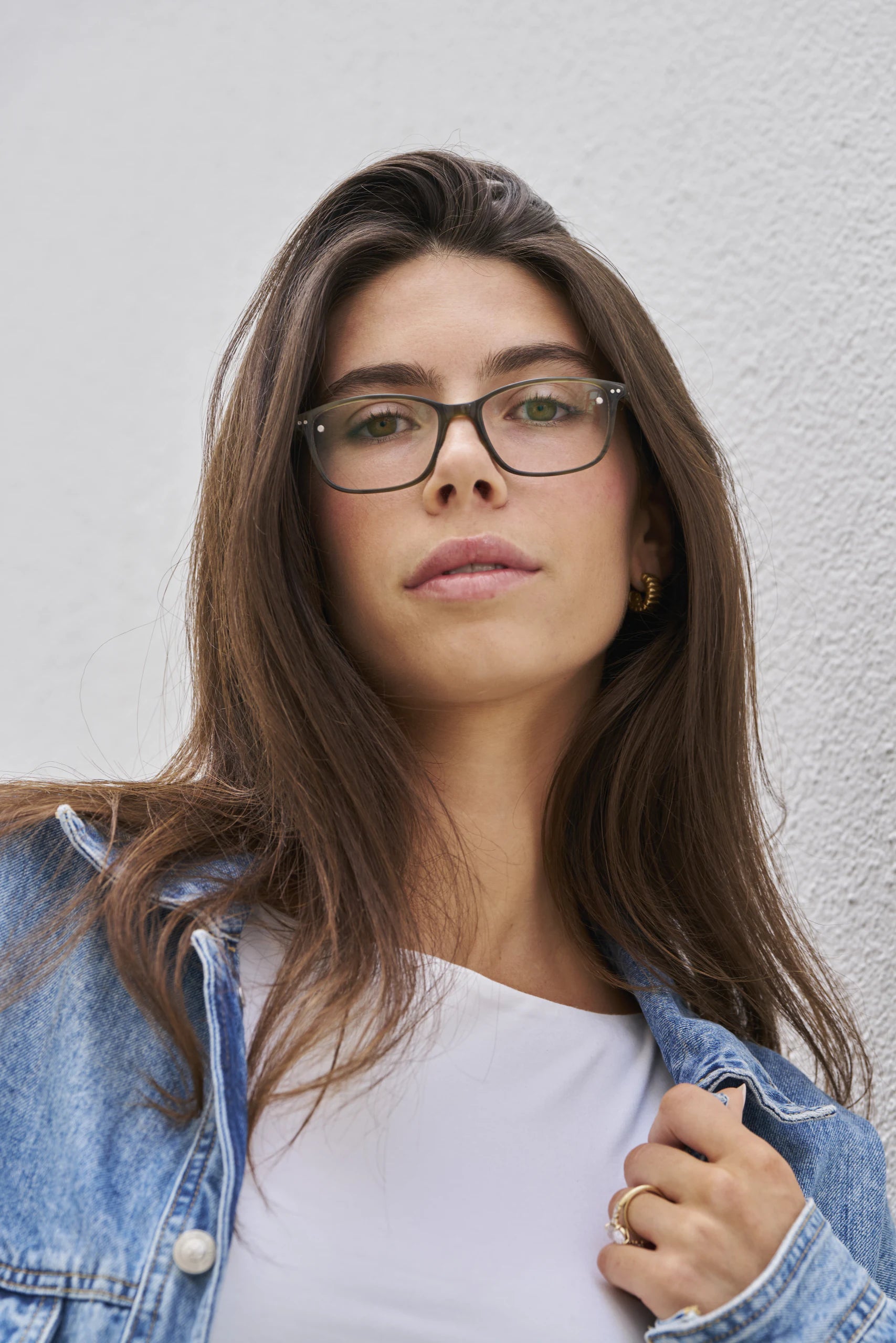 A woman in a denim jacket wearing clear Chemistrie eyeglasses